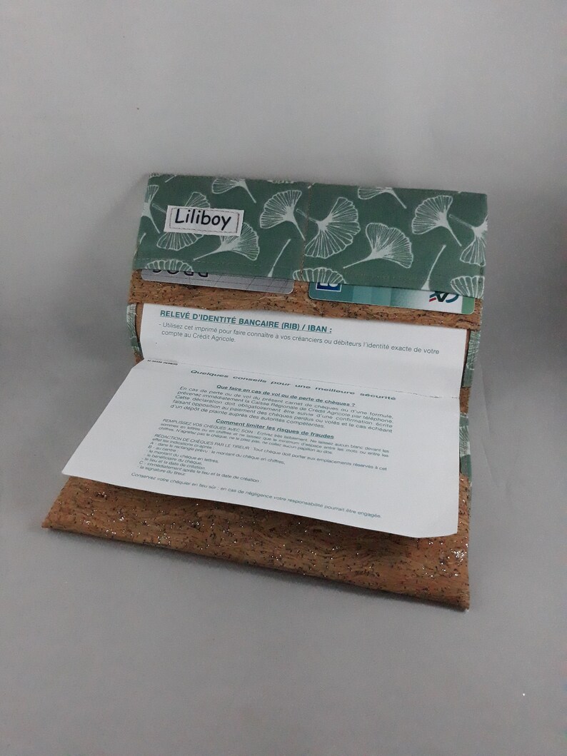 May include: A wallet with a cork base and a green fabric top featuring a white leaf pattern. The wallet is open, revealing a paper document and card slots. The text "Liliboy" is visible on the top.