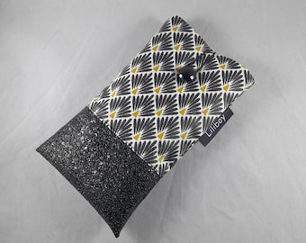 May include: A rectangular case with a black, glittery bottom half and a patterned top half. The top half features a white background with a repeating black and yellow fan-like design. A black button secures the case. The label reads "Liliboy".