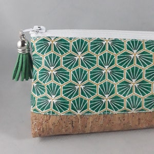 May include: A small, rectangular pouch with a white zipper and a green tassel. The pouch features a geometric pattern in green and gold, with a cork base. The zipper pull is silver.