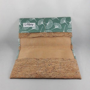 May include: Open wallet with a light green flap featuring a white leaf pattern. The wallet's body is made of cork material. The brand name "Liliboy" is printed on the flap.