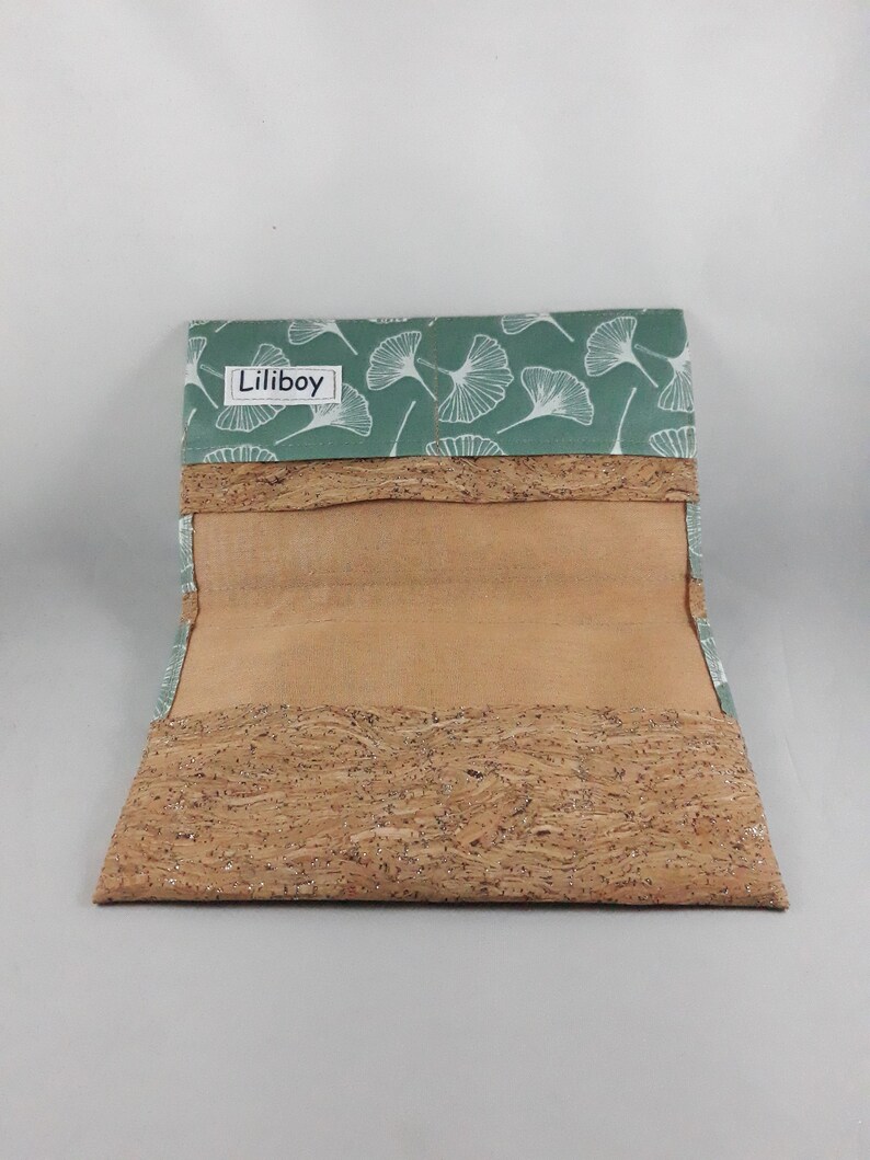 May include: Open wallet with a light green flap featuring a white leaf pattern. The wallet's body is made of cork material. The brand name "Liliboy" is printed on the flap.