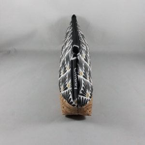 May include: A patterned cosmetic bag in black and white with a gold accent and a cork base. The bag has a black zip and the word "liliboy" printed on the side.