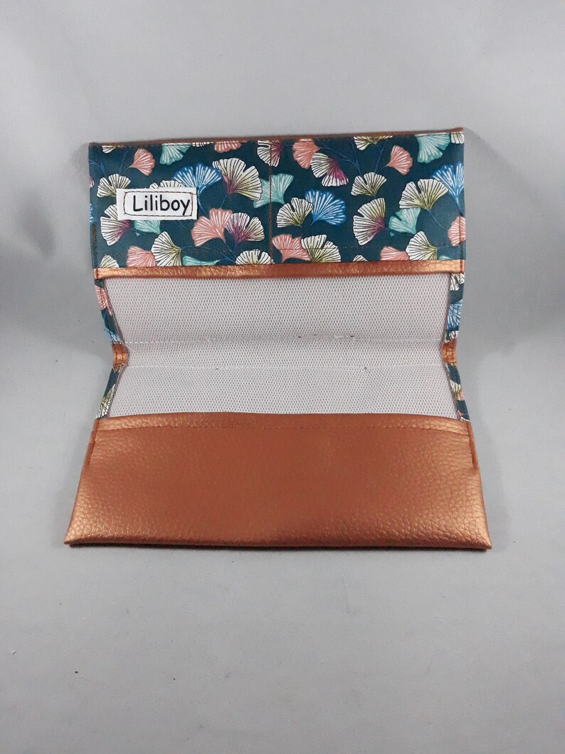 May include: Open eyeglass case with a teal, pink, and blue floral pattern. The case has a copper-colored trim and a copper-colored leather bottom. The interior is white mesh. The text "Liliboy" is visible on the top flap.