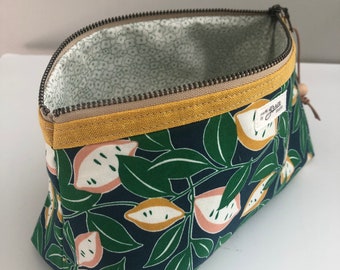 May include: A navy blue zippered pouch with a yellow trim and a floral print of lemons and leaves. The pouch is lined with a white fabric with a small floral pattern. The pouch has a label that says "made with grace".