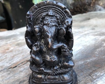 Op de afbeelding: Zwart stenen beeld van Ganesha, de hindoeïstische god van wijsheid en voorspoed, zittend op een lotusthron. Het beeld is ingewikkeld gebeeldhouwd met details van Ganesha's slurf, oren en slagtanden.