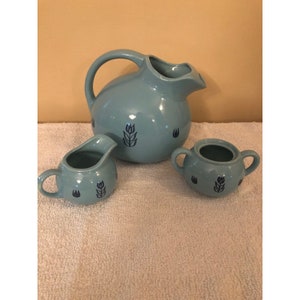 Può includere: Un set vintage di brocca, lattiera e zuccheriera in ceramica blu con un motivo a spiga di grano. Il set è in buone condizioni, senza scheggiature o crepe.