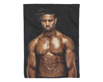 May include: A shirtless man with a muscular physique and dreadlocks poses against a black background. He has a serious expression on his face.
