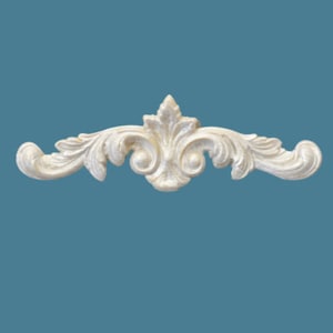 May include: An off-white, horizontal decorative molding piece featuring a symmetrical, raised relief design with intricate acanthus leaf scrolls and a central pointed floral motif, crafted with a smooth, matte finish.
