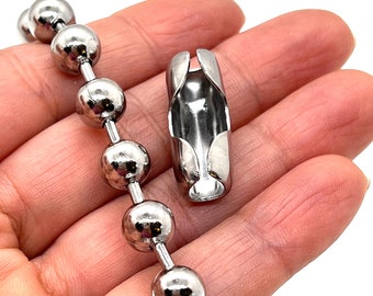 May include: A silver-toned metal ball chain featuring a series of spherical beads connected by short links, accompanied by a matching cylindrical metal connector clasp with an open slot design for securing the chain ends together.