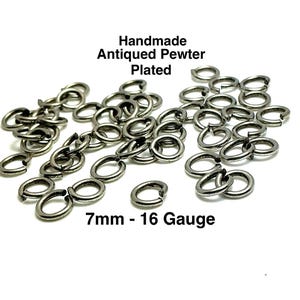 Peut inclure: Un ensemble de anneaux de saut faits à la main, en étain vieilli plaqué. Les anneaux sont de couleur argent foncé et sont ouverts, avec un diamètre de 7 mm et une épaisseur de calibre 16. Le texte "Handmade Antiqued Pewter Plated" et "7mm - 16 Gauge" est visible.