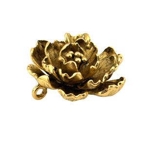 May include: A detailed, golden-colored metal flower with multiple petals and a small loop. The flower's design is intricate, with textured surfaces and a realistic appearance. The overall aesthetic is vintage or antique.