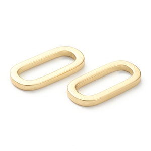 May include: Two gold oval-shaped metal rings. The rings are smooth and have a shiny finish.