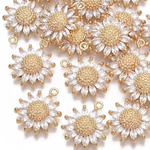 May include: A group of gold-tone sunflower charms with clear crystal accents. Each charm has a loop for attaching to jewelry or other crafts.