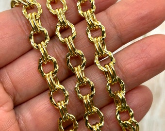 May include: Close-up of three gold-colored chain necklaces. Each chain is composed of interlocking oval links with a textured, twisted design. The chains are displayed against a neutral background, highlighting their bright, reflective surface.