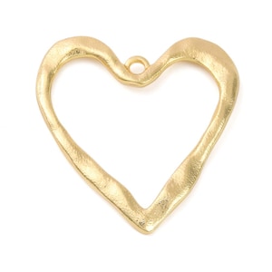 May include: A gold-colored heart-shaped pendant with a textured, matte finish. The heart is open in the center and features a small circular loop at the top for attachment, showcasing a hammered metal appearance with irregular, organic edges.