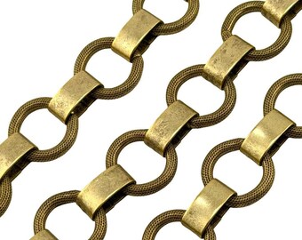 May include: Close-up of a decorative chain with a repeating pattern. The chain links are a warm brass color, with a textured, mesh-like appearance in the circular links. Rectangular brass-colored bars connect the circular links. The background is white.