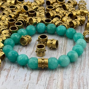 May include: A white ceramic mug with a black handle and the text "But First, Coffee" in a bold, black font. The mug is set against a blurred background, suggesting a cozy setting.