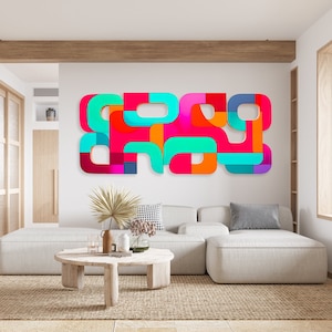 May include: A white sectional sofa with a colorful abstract wall art piece above it. The wall art is made of various shapes and colors, including teal, pink, orange, and red. The sofa is in a modern living room with a wooden coffee table and a green plant.