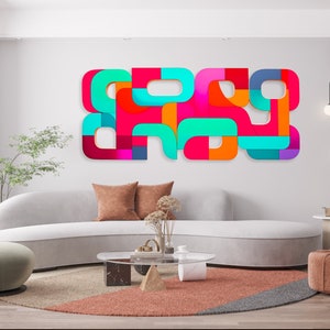 May include: A modern living room with a white curved sofa, a round coffee table, and a colorful abstract wall art piece. The art piece is made of geometric shapes in shades of red, orange, yellow, green, blue, and purple.