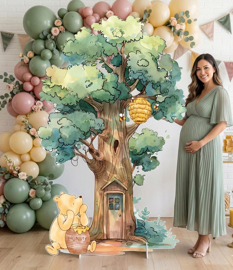 Puede incluir: Un gran recorte de cart&oacute;n independiente que presenta una ilustraci&oacute;n estilo acuarela de un &aacute;rbol con una colmena, una peque&ntilde;a puerta en la base y Winnie the Pooh sentado junto a un tarro de miel con la etiqueta HUNNY, ante un arco de globos.
