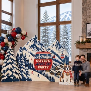 May include: A large mountain-themed party backdrop featuring a red ski gondola with the text OLIVER'S APRES SKI PARTY, surrounded by snowy peaks, pine trees, and a Saint Bernard dog cutout, accented by a balloon arch in red, white, and blue.