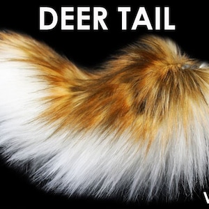 May include: A faux deer tail, approximately 7 inches long, with a mix of white, brown, and reddish-brown fur. The text "DEER TAIL" is at the top, and "7"" is at the bottom left. The brand name "VUZARA" is at the bottom right.