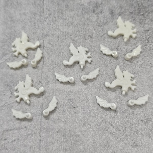 May include: A set of white plastic dragon and wing pieces. The pieces are designed to be used for crafts or decorations.