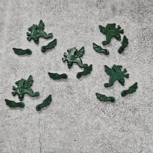 May include: A set of 10 green plastic dragon figurines. The dragons are in various poses and have wings and tails. The figurines are ideal for adding a touch of whimsy to any craft project.