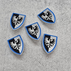 May include: Five silver shields with a black and white eagle design and a blue trim. The shields are on a gray textured surface.