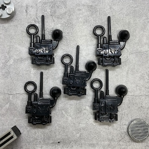 May include: Five black plastic toy walkie talkies with antennas and round black buttons.