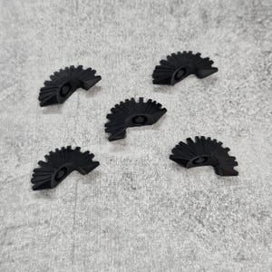 May include: Five black plastic gears with a circular shape and a pointed edge. The gears have a raised center with a small hole in the middle.