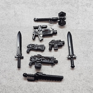 Puede incluir: Un surtido de armas de juguete negras, que incluyen dos espadas, un martillo y varias pistolas. Las armas son de plástico y están dispuestas sobre una superficie gris. La colección incluye varios diseños, como un martillo con cabeza geométrica y una espada con guarda cruzada.