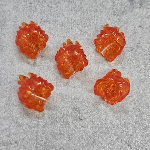 Może przedstawiać: Pięć pomarańczowych plastikowych spinek do włosów w kształcie płomieni. Spinki są przezroczyste i mają błyszczące wykończenie.