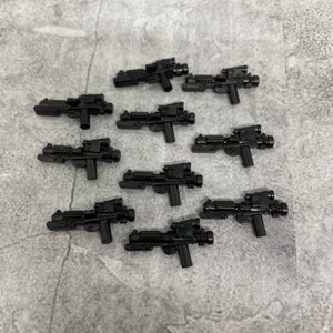 May include: Ten black plastic toy blasters with a futuristic design. The blasters have a scope and a handle.