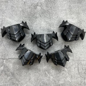 May include: Five black plastic pieces with a geometric design. Each piece has a pointed edge on either side and a curved edge on the bottom.