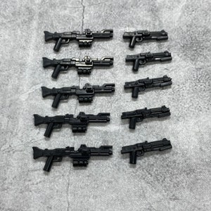 May include: Eight black plastic toy blasters with different designs. The blasters have a futuristic look and are made of a smooth, matte plastic.