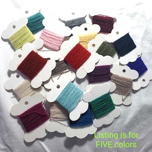 May include: A collection of embroidery floss wound onto white cardboard bobbins in various colors including red, blue, green, yellow, pink, purple, brown, and beige. The text "Listing is for FIVE colors" is printed in green in the bottom right corner.