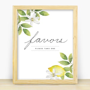 Op de afbeelding: Een wit bord met een houten frame en een citroen- en bloeiende ontwerp. Het bord zegt "favors" en "please take one".