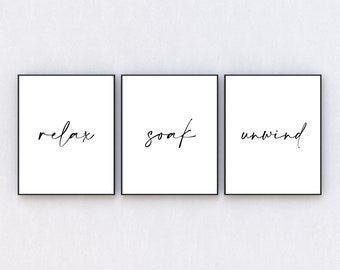 May include: Three black framed prints with white backgrounds and black calligraphy. The prints read "relax", "soak", and "unwind".