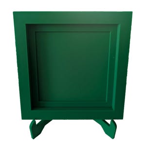 以下が含まれることがあります： スタンド付きの濃い緑色の写真フレーム。フレームは二重の縁取りで、木でできています。