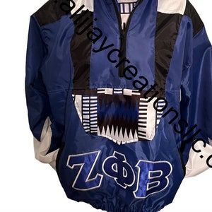 May include: A blue, black, and white hooded anorak jacket with a half-zip closure. The jacket features a geometric pattern on the hood and the letters "ZΦB" on the front. The website address "alijaycreationsllc.com" is visible.