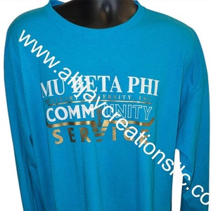 May include: A turquoise long-sleeved shirt featuring white and gold text. The text on the shirt reads "MU BETA PHI MILITARY FRATERNITY, INC. COMMUNITY SERVICE". The shirt is displayed on a black mannequin.
