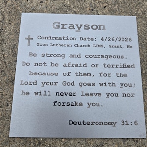 May include: A gray rectangular card with the name "Grayson" at the top. The card includes a cross symbol, confirmation details, and a Bible verse from Deuteronomy 31:6.