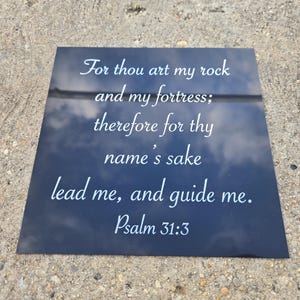 May include: A dark blue square plaque with white script. The text reads, "For thou art my rock and my fortress; therefore for thy name's sake lead me, and guide me. Psalm 31:3."