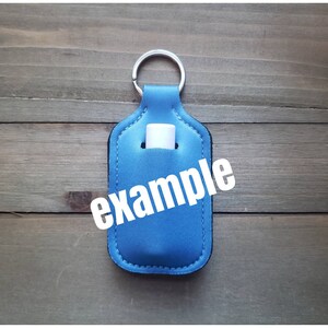 Pu&ograve; includere: Portachiavi in tessuto blu con un porta-tubo bianco e la parola "esempio" stampata sul davanti.
