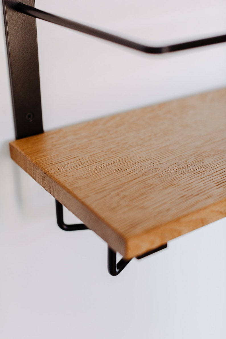 K&ouml;nnte beinhalten: Ein Holzregal mit schwarzen Metallkonsolen. Das Regal ist aus hellem Holz mit nat&uuml;rlicher Maserung.