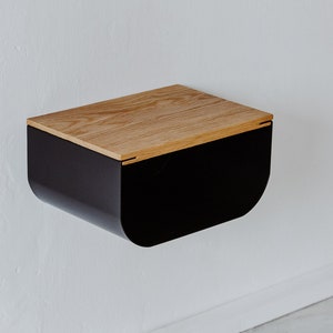 May include: A black wall-mounted nightstand with a curved front and a wood top.