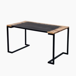 May include: A black metal table with a rectangular wooden top. The top is stained black with a natural wood edge.