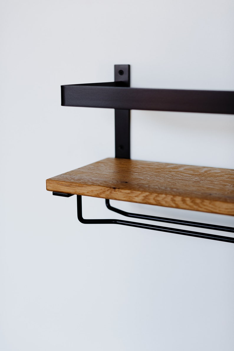May include: A black metal shelf with a wooden top and a metal wine rack underneath. The shelf is mounted to a white wall.
