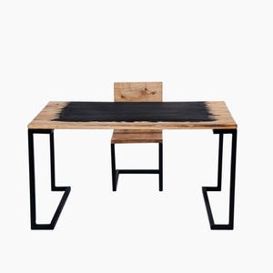 May include: A black and wood desk with a black metal frame and a matching chair. The desk has a black top with a wood grain pattern.